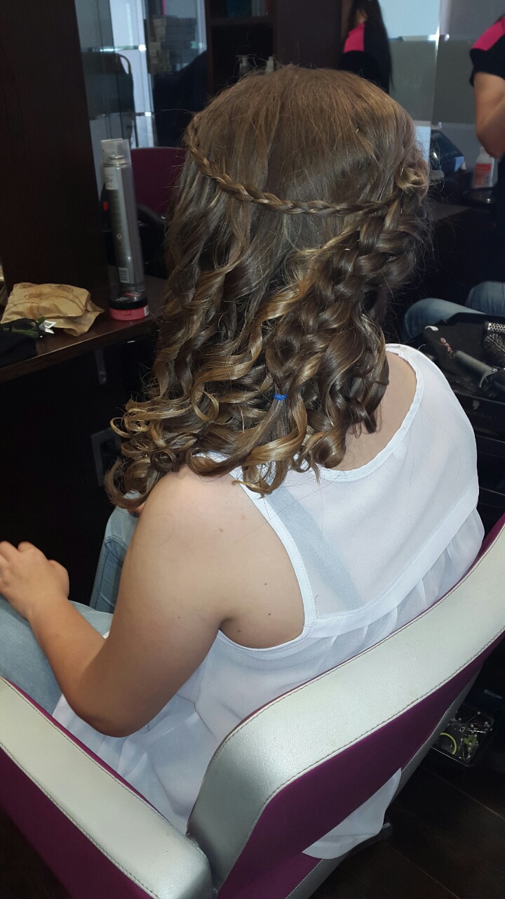 Client's hair styled with braids and curls in a salon chair